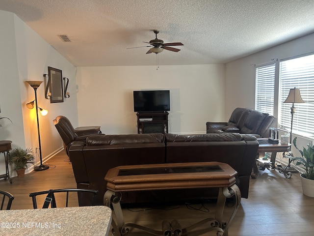 living room featuring ceiling fan, a textured ceiling, and hardwood / wood-style flooring