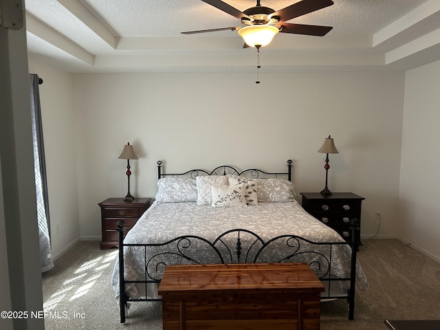 bedroom with ceiling fan, carpet floors, a textured ceiling, and a tray ceiling