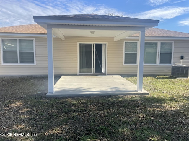 back of property with central AC unit, a patio area, and a lawn