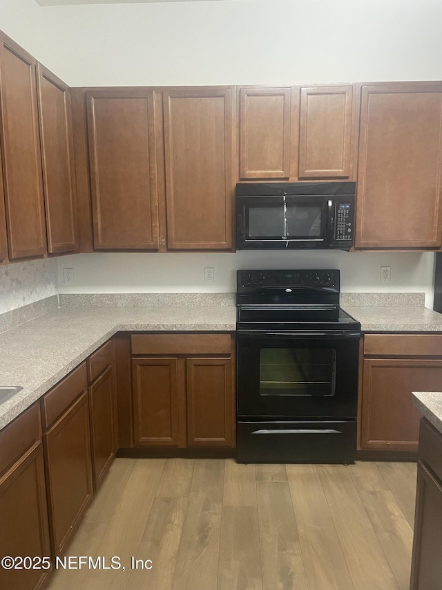 kitchen with light wood-type flooring and black appliances