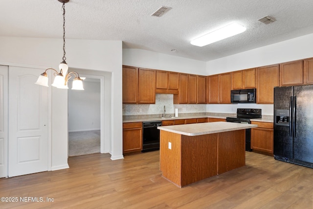 11786 Huckleberry Trl E, Macclenny, FL 32063 - kitchen with black appliances, a chandelier, light wood-style floors, brown cabinets, and a textured ceiling