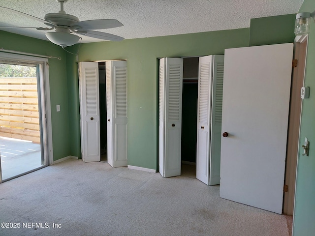 unfurnished bedroom featuring access to outside, ceiling fan, light colored carpet, and two closets