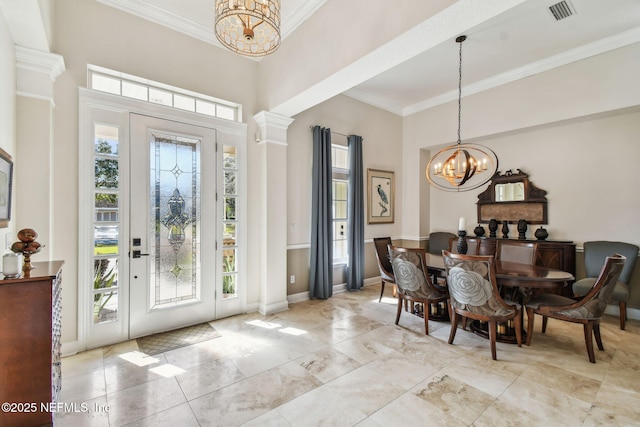 foyer with a notable chandelier, ornamental molding, and decorative columns