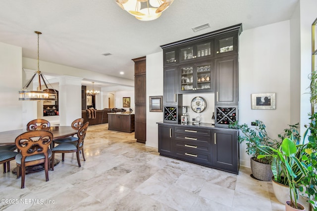 bar featuring decorative light fixtures, dark brown cabinetry, a textured ceiling, and an inviting chandelier