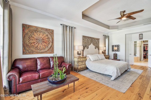 bedroom featuring a raised ceiling, ceiling fan, hardwood / wood-style floors, and crown molding