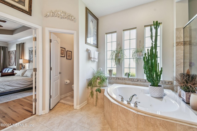 bathroom with toilet and tiled tub