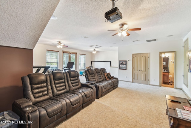 cinema room featuring ceiling fan, carpet, and a textured ceiling