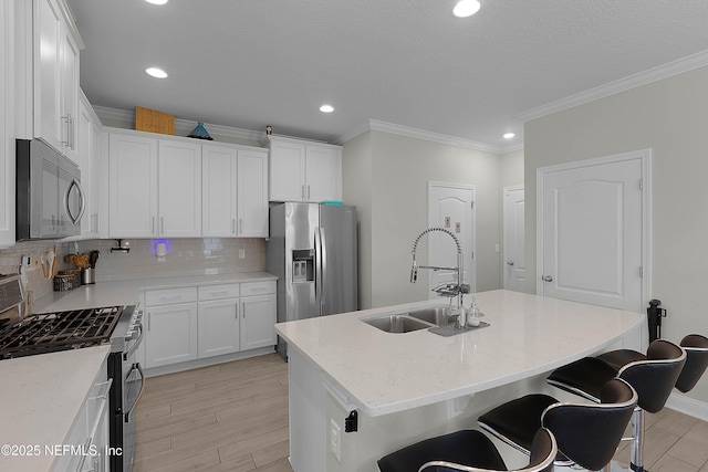 kitchen with white cabinetry, sink, a breakfast bar area, stainless steel appliances, and a center island with sink