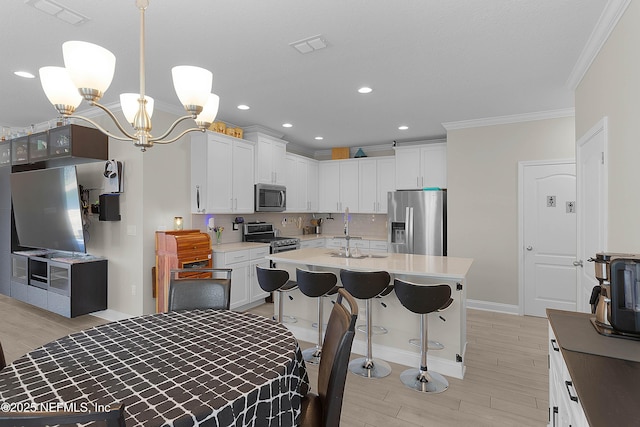 kitchen with white cabinetry, sink, hanging light fixtures, and appliances with stainless steel finishes