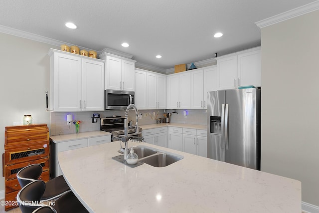 kitchen with light stone countertops, ornamental molding, appliances with stainless steel finishes, and white cabinets