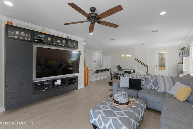 living room with crown molding, ceiling fan with notable chandelier, and light wood-type flooring