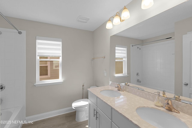 full bathroom featuring tiled shower / bath combo, wood-type flooring, vanity, and toilet