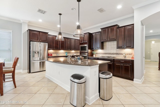 kitchen with decorative light fixtures, tasteful backsplash, a center island with sink, appliances with stainless steel finishes, and light tile patterned floors