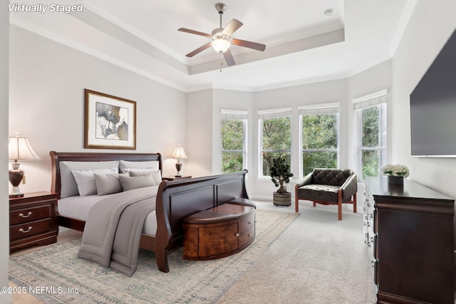 bedroom featuring ceiling fan, light colored carpet, a tray ceiling, and crown molding