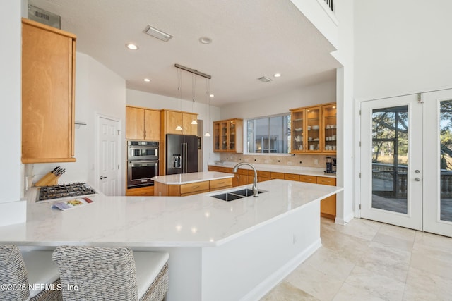 kitchen with kitchen peninsula, pendant lighting, black fridge with ice dispenser, sink, and a center island with sink