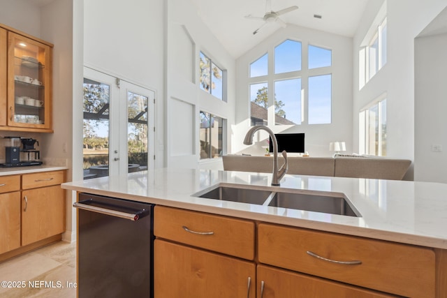 kitchen featuring light tile patterned floors, stainless steel dishwasher, sink, high vaulted ceiling, and light stone counters