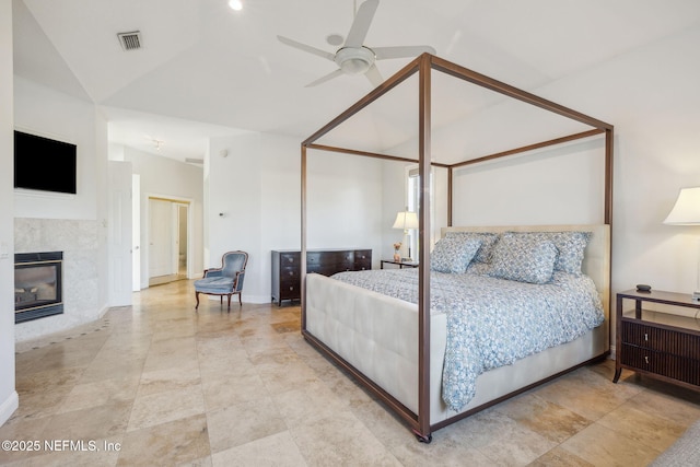 bedroom featuring ceiling fan, a tile fireplace, and lofted ceiling