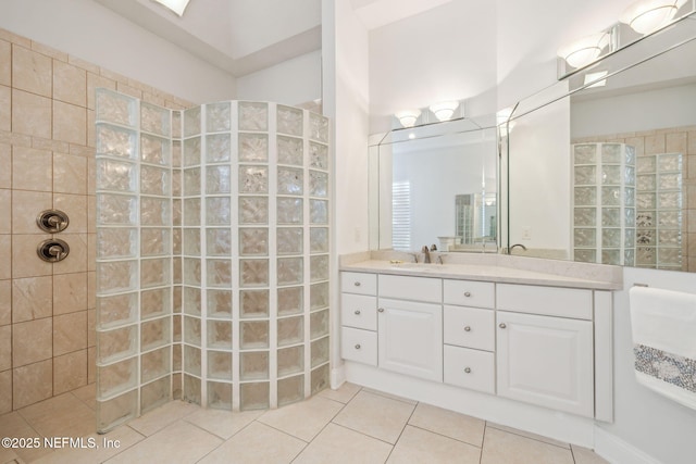 bathroom featuring tiled shower, tile patterned flooring, and vanity