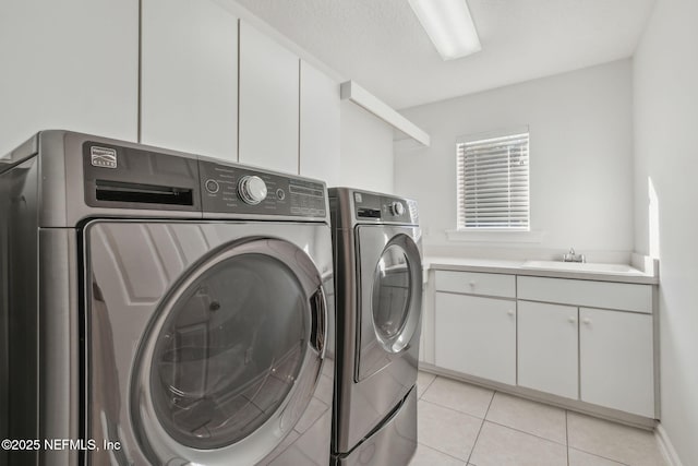 laundry room featuring sink, washer and clothes dryer, light tile patterned floors, and cabinets