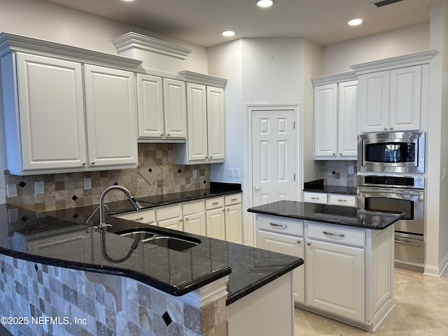 kitchen featuring white cabinets, dark stone countertops, sink, and appliances with stainless steel finishes