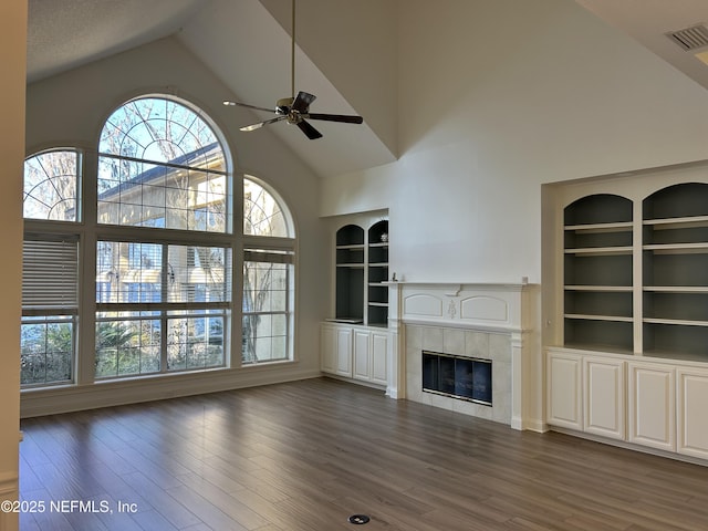 unfurnished living room featuring a fireplace, built in features, high vaulted ceiling, and a healthy amount of sunlight