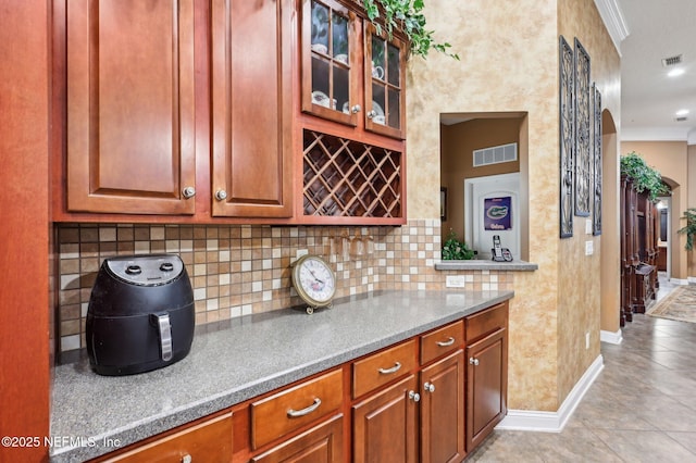 kitchen featuring light tile patterned flooring, ornamental molding, and decorative backsplash