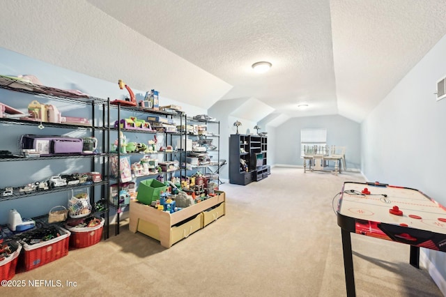 playroom featuring lofted ceiling, carpet floors, and a textured ceiling