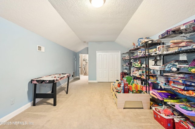 game room featuring vaulted ceiling, light carpet, and a textured ceiling