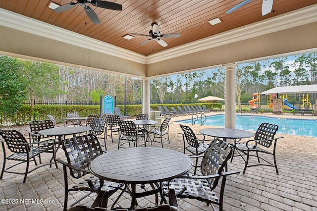 view of patio featuring ceiling fan, a community pool, and a playground