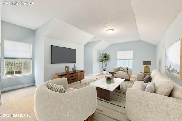 living room with lofted ceiling, a healthy amount of sunlight, light carpet, and a textured ceiling