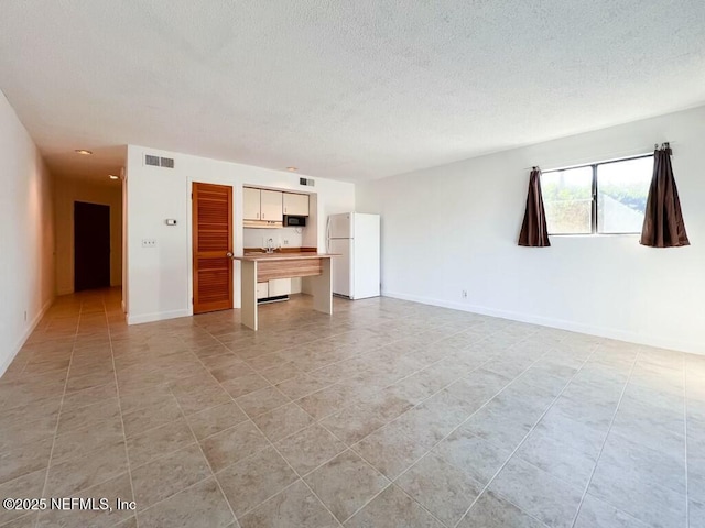 unfurnished living room featuring light tile patterned floors and a textured ceiling