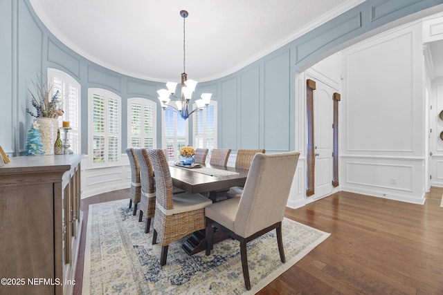 dining room with an inviting chandelier, crown molding, and dark hardwood / wood-style floors