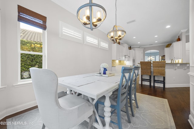 dining space featuring crown molding, a healthy amount of sunlight, a notable chandelier, and dark hardwood / wood-style floors