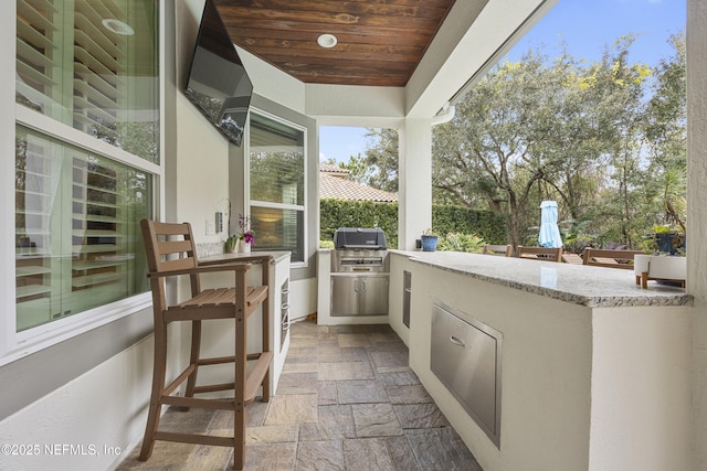 view of patio with an outdoor kitchen, exterior bar, and a grill