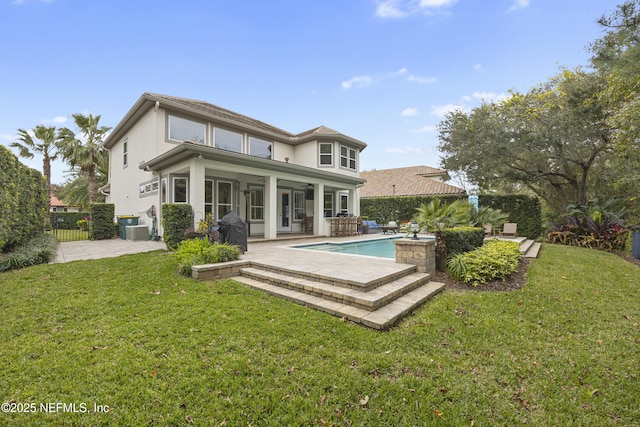 rear view of property featuring a patio area, central AC unit, a fenced in pool, and a yard