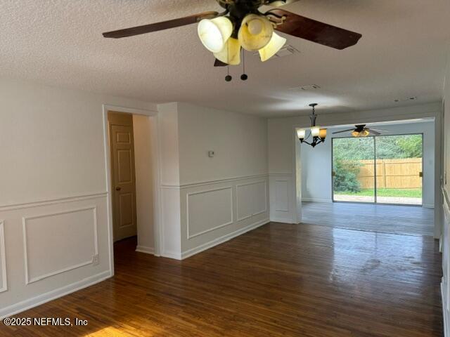 spare room with a chandelier, a textured ceiling, and dark hardwood / wood-style floors