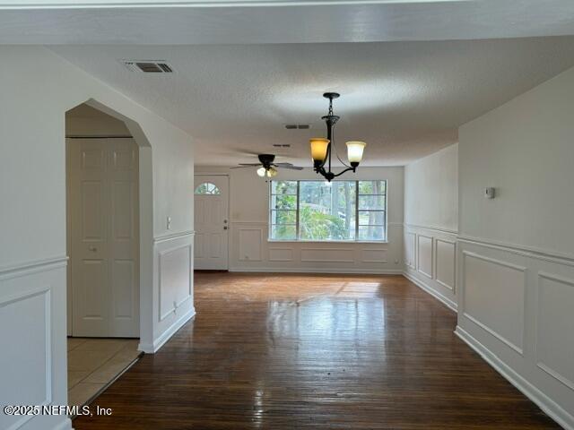 unfurnished dining area featuring hardwood / wood-style floors and ceiling fan with notable chandelier