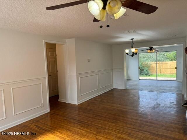 spare room featuring a chandelier, a textured ceiling, and dark wood-type flooring