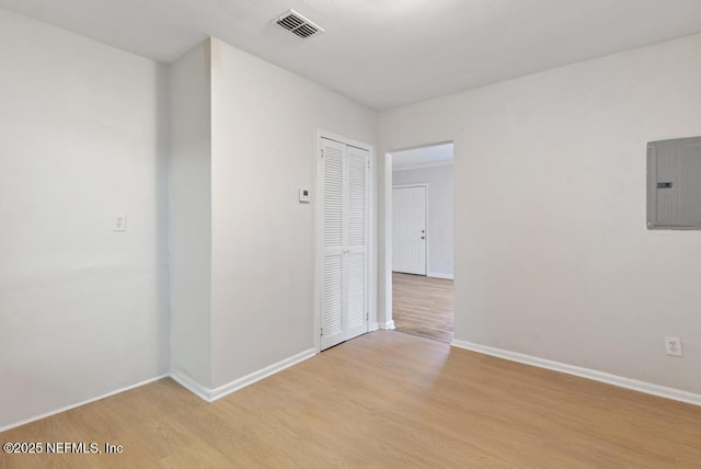 spare room with electric panel and light hardwood / wood-style flooring