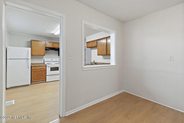 kitchen with light wood-type flooring, white appliances, sink, and exhaust hood