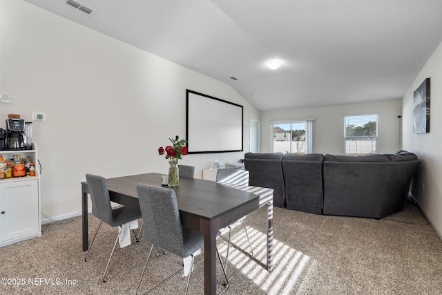 carpeted dining area featuring lofted ceiling