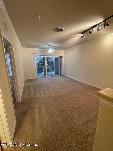 spare room featuring rail lighting, a textured ceiling, ceiling fan, crown molding, and carpet floors