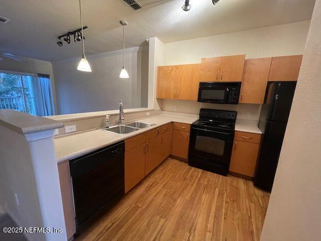 kitchen with kitchen peninsula, sink, black appliances, pendant lighting, and light hardwood / wood-style flooring