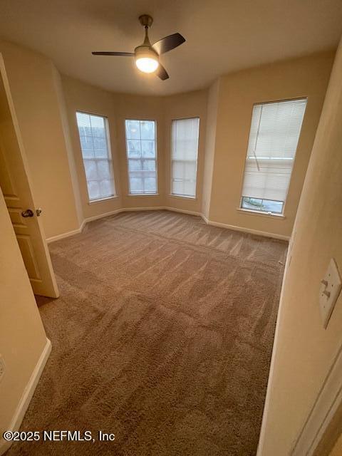 carpeted spare room featuring ceiling fan