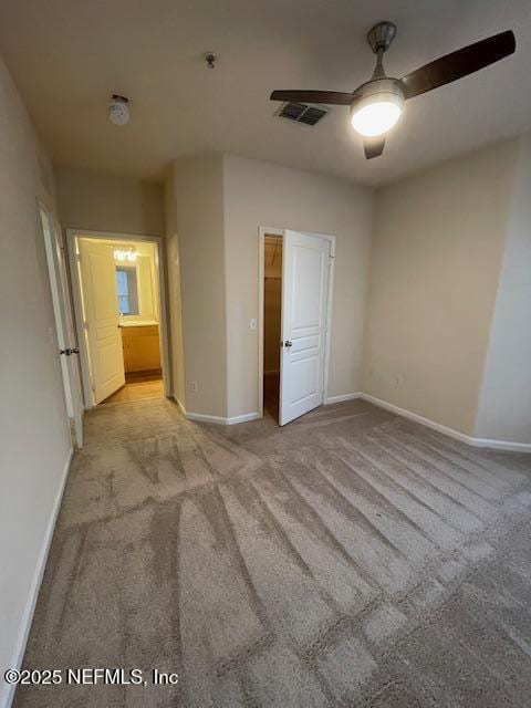 unfurnished bedroom with connected bathroom, light carpet, and ceiling fan