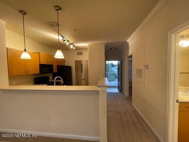 kitchen featuring kitchen peninsula, rail lighting, ornamental molding, sink, and black appliances