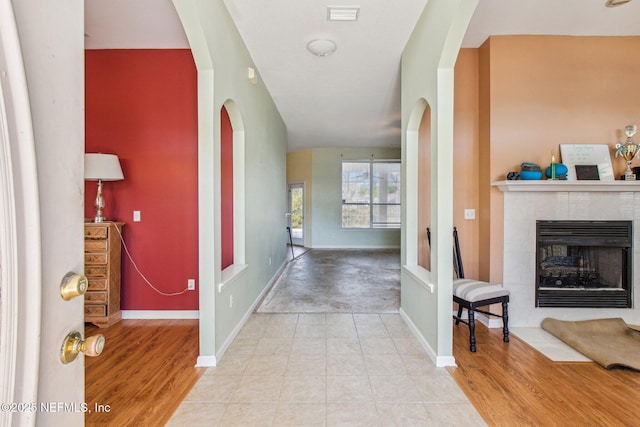 foyer entrance with a tile fireplace and light hardwood / wood-style flooring