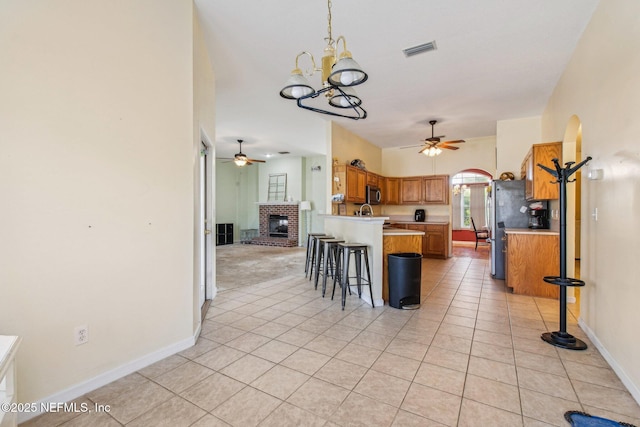 kitchen featuring light tile patterned floors, ceiling fan with notable chandelier, a breakfast bar area, and appliances with stainless steel finishes