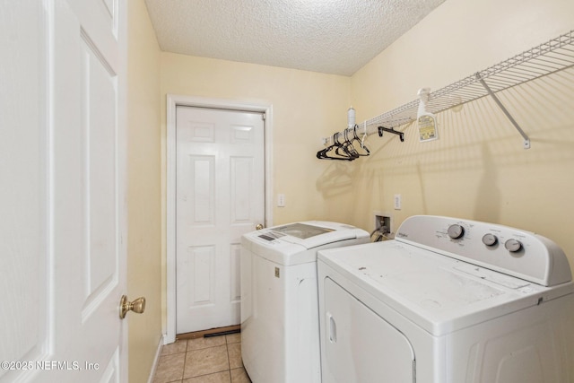 laundry room featuring light tile patterned floors, washer and dryer, and a textured ceiling