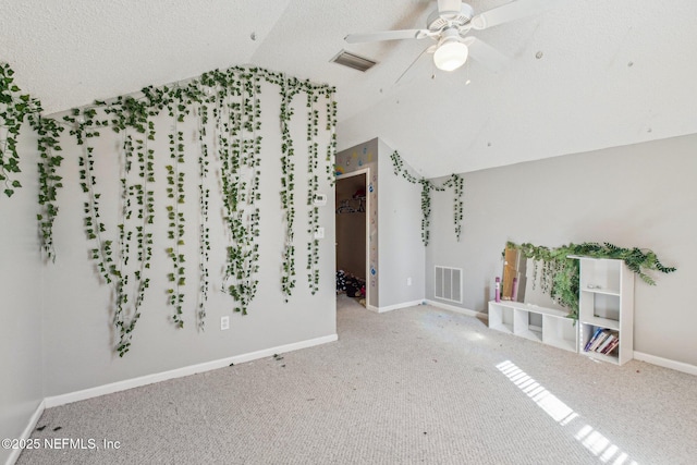 unfurnished living room with vaulted ceiling, carpet flooring, a textured ceiling, and ceiling fan